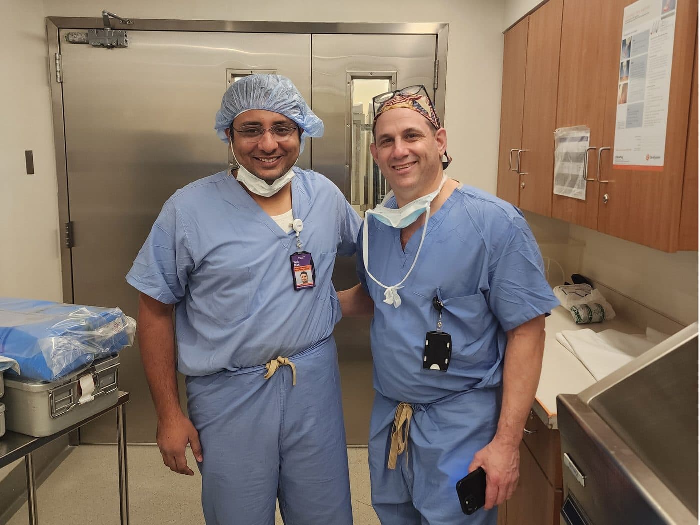 Dr. Yash Shah in surgical scrubs with a senior surgeon during international training
